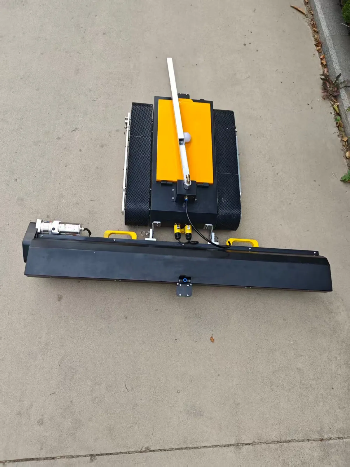 Cleaning robot seen from above, brush bar ahead of the tracks